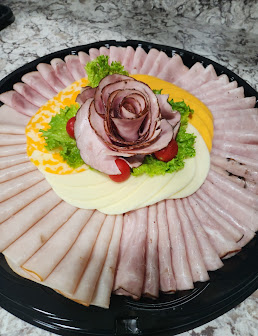Deli tray of sliced ham, cheeses and lettuce with a ham rose in the center